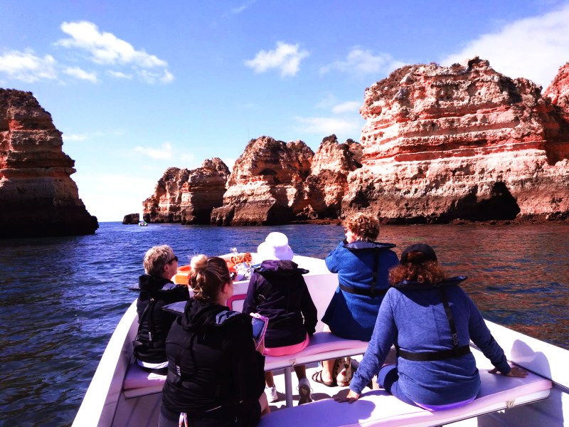 a group of people sitting on a boat next to a body of water